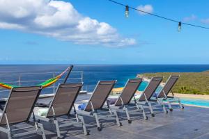 a row of chairs sitting next to a swimming pool at Villa Lahara with spectacular views in Dorp Soto