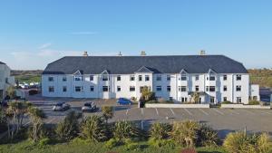 a large white building with cars parked in a parking lot at Lagoon View - Sea View- Pet Friendly - 2 Bed Apt - En-suite in Trearddur