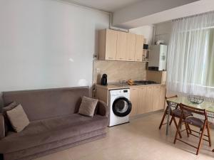 a living room with a couch and a table and a kitchen at Studio Summerland in Mamaia