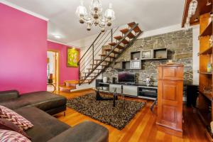 sala de estar con paredes de color rosa y pared de piedra. en Casa Rocha, en Fajã da Ovelha 19 fotos más