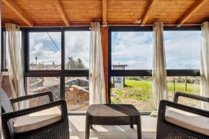 Habitación con 2 sillas y ventana grande. en Casa Rocha, en Fajã da Ovelha