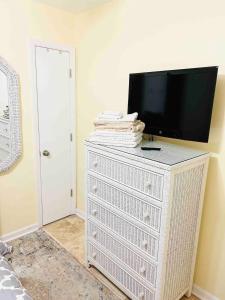 a tv on top of a white dresser in a room at Sea Breeze, Beautiful Ocean Front Townhome in Kure Beach