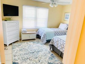a bedroom with two beds and a flat screen tv at Sea Breeze, Beautiful Ocean Front Townhome in Kure Beach