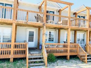 a wooden house with a large deck and stairs at Sea Breeze, Beautiful Ocean Front Townhome in Kure Beach