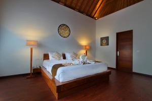 a bedroom with a large bed and a clock on the wall at Bali Nyuh Gading Villas in Seminyak