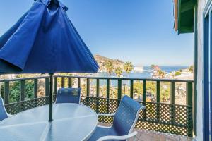 a table and chairs with a blue umbrella on a balcony at 130MT 130 Middle Terrace in Avalon