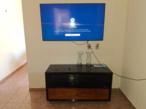 a tv on a wall with two glasses on a table at Casa Para TECNOSHOW Comigo Rio Verde GO in Rio Verde