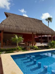 a resort with a thatched roof and a swimming pool at Casa pedregal in Cancún