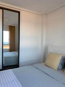 a white bedroom with a bed and a mirror at Cabo Cervera Sea View in Torrevieja