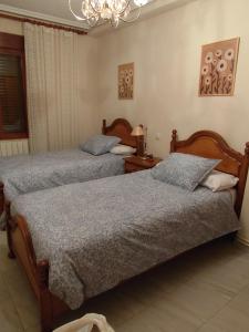 a bedroom with two beds and a chandelier at Casa Rural Pesquera de Duero in Pesquera de Duero