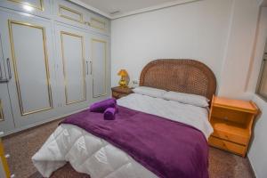 a bedroom with a purple blanket on a bed at Sweetstaybykw Dean Llopez Stay in Santa Pola
