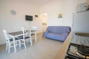 a kitchen and dining room with a table and a couch at Casa Verde Mare in La Caletta +12 photos
