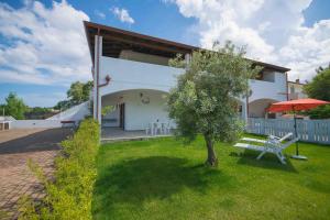 a white house with a tree in the yard at Casa Verde Mare in La Caletta