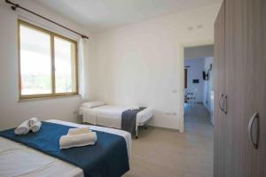 a white room with two beds and a window at Casa Verde Mare in La Caletta
