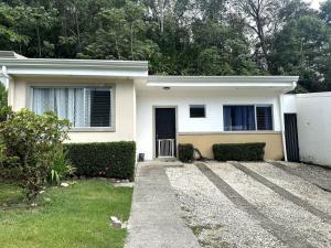 a white house with a door and some bushes at Herradura casa vacacional in Herradura