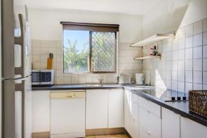 a white kitchen with a sink and a window at Sunny Somerset 2B located opp Byron Bay markets in Byron Bay