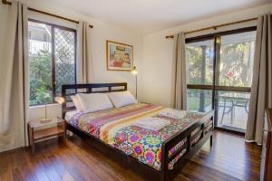 a bedroom with a bed in a room with windows at Sunny Somerset 2B located opp Byron Bay markets in Byron Bay