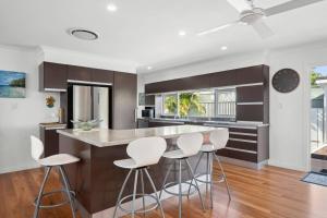 une cuisine avec des tabourets blancs et un grand îlot dans l'établissement Bels Florida Family Getaway - Pool, WiFi, BBQ, à Gold Coast