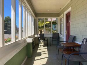 a porch with chairs and tables and windows at Henderson Hideout Hot Tub and Pet Friendly. in Eureka