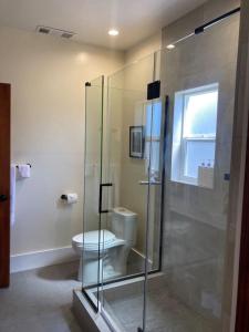 a bathroom with a toilet and a glass shower at Henderson Hideout Hot Tub and Pet Friendly. in Eureka +8 photos