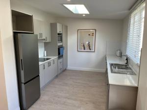 a kitchen with white cabinets and a sink and a refrigerator at Beautiful comfortable cottage in Orange +9 photos