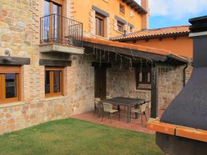 a patio with a table and chairs and a building at La Traviesa de la Demanda in Cabezón de la Sierra