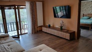 a living room with a couch and a tv on the wall at Cabana Ene Strada Poienari nr 13 A in Râmnicu Vâlcea