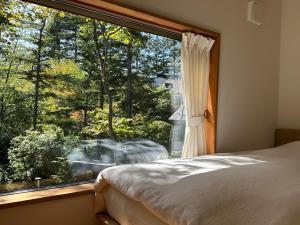 a bedroom with a window looking out at a garden at Karuizawa Mori Shiki VILLA - Vacation STAY 57077v in Kutsukake