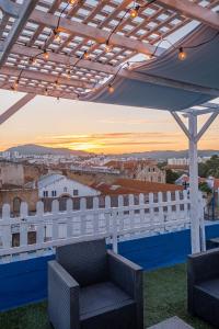 a balcony with a white fence and chairs and a sunset at Y Quebedo - Boutique Apartments in Setúbal