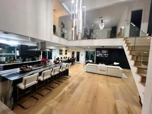 a kitchen and living room with a bar with white chairs at Luxury Home w Pool, Open Kitchen, Poker Room & More in Dallas