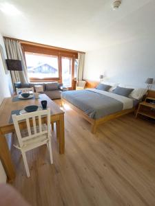 a bedroom with a bed and a table and a couch at Studio with balcony, Niesen view & free parking near Interlaken, Thunersee & Blausee in Aeschi bei Spiez