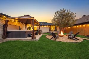 un patio trasero con una hoguera y una sombrilla en Zen Back Yard with Hot Tub, Firepit, Spa at Home, en Dallas