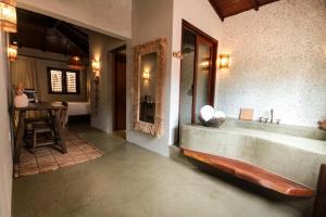 a bathroom with a large tub and a table at Caraíva Villas de Jardel - Casa Principal in Caraíva +10 photos