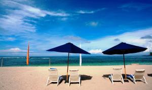 a group of chairs and umbrellas on a beach at Pool Villa Merumatta Senggigi in Senggigi
