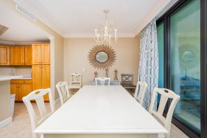 a kitchen and dining room with a white table and chairs at Phoenix on the Bay 1429 condo in Orange Beach