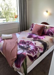 a bed with a purple flower blanket on it at Horseinaround in Cambridge