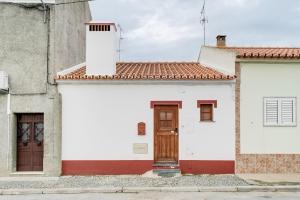 a white and red building with a brown door at Casa da Junqueira-Alqueva in Campinho