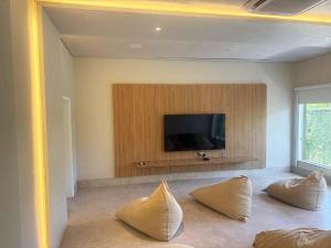 a living room with a tv and two pillows at Exclusiva Casa 18G em Juqueí em Condomínio Resort de Luxo in Juquei