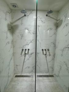 a bathroom with a shower with white marble walls at Av Suites in Rosario +138 photos