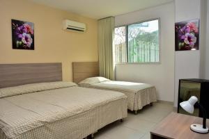 a hotel room with two beds and a window at HOTEL AQUARELLA DEL MAR in Santa Marta