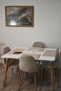 a dining room table with chairs and a painting on the wall at Joneal Apartment in Shkodër +6 photos