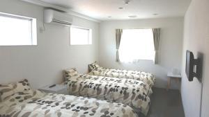 a bedroom with two beds and two windows at Shima Stay holoholo in Zamami