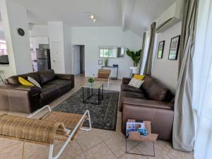 a living room with leather couches and a table at Stableford Cottage Holiday Home Dunsborough in Dunsborough