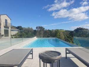 a swimming pool with a table and a table and a stool at Cable Bay Luxury Villa in Oneroa