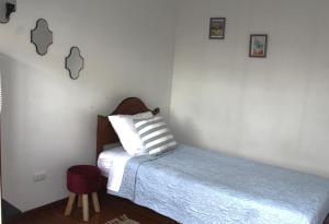 圣地亚哥Aero Hostal的一间卧室配有一张带枕头和凳子的床