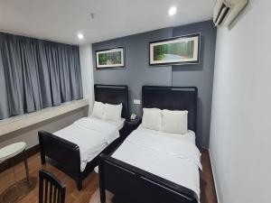 a small room with two beds and a chair at Hotel O Crossroads Hotel in Kuala Lumpur