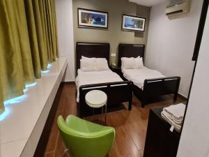 a room with two beds and a green chair at Hotel O Crossroads Hotel in Kuala Lumpur
