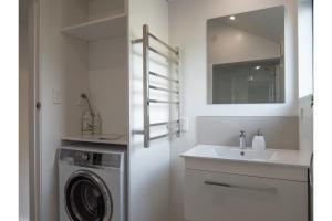 a bathroom with a sink and a washing machine at Tawa Retreat - Wellington Holiday Home in Wellington