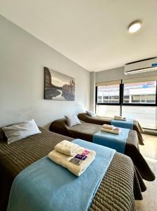 a bedroom with three beds and a large window at Av Suites in Rosario