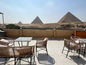 un patio con tavoli e sedie con piramidi sullo sfondo di Tamara Pyramids View a Il Cairo